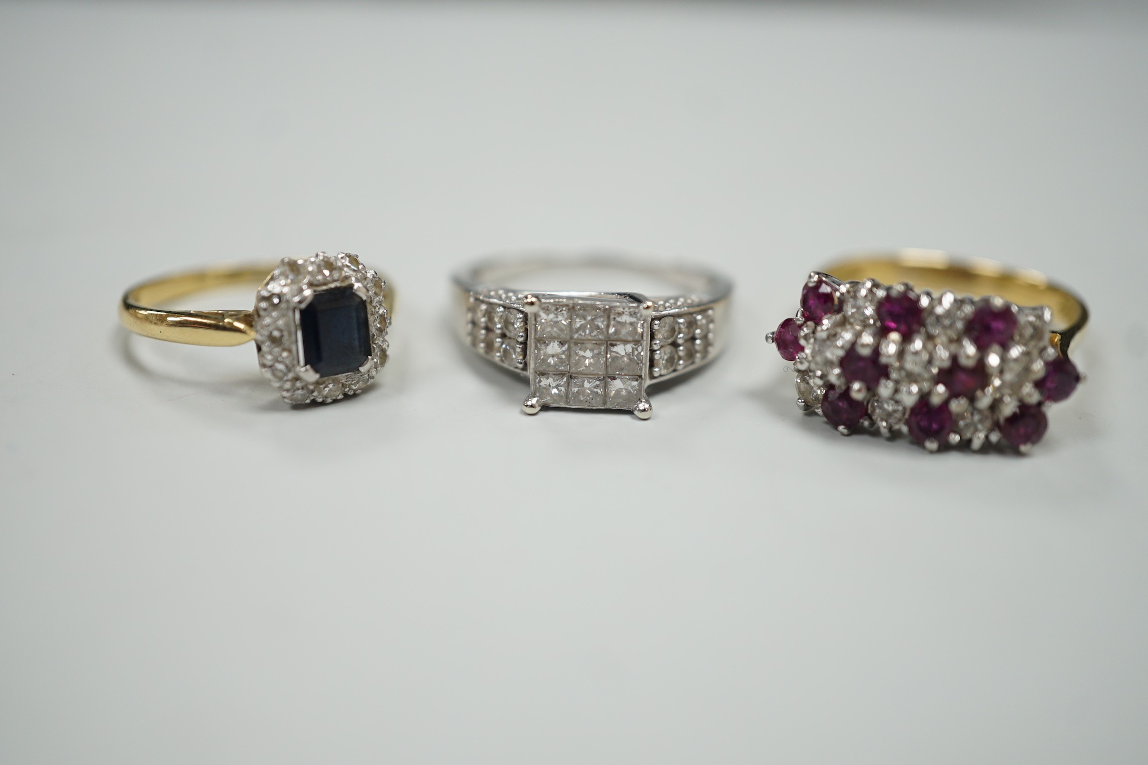 Three assorted modern gem set rings, including white metal and diamond cluster tablet ring with diamond set shoulders, an 18ct gold, sapphire and diamond cluster set ring and an 18ct gold ruby and diamond set cluster rin